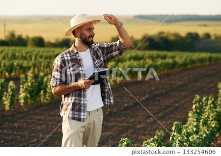 In the straw hat. Farmer is on the agricultural field 133254606