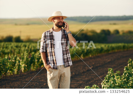 Talking by a phone. Farmer is on the agricultural field 133254625