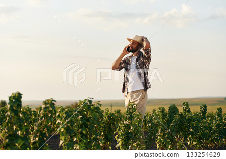 Talking by a phone. Farmer is on the agricultural field 133254629