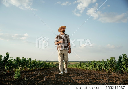 Front view, walking forward. Farmer is on the agricultural field Front view, walking forward. Farmer is on the agricultural field 133254687
