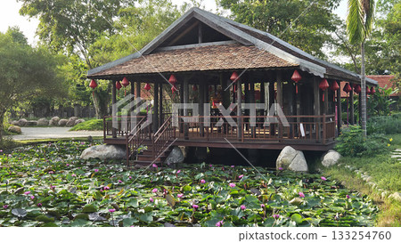 Traditional wooden pavilion with red lanterns overlooking pond f Traditional wooden pavilion with red lanterns overlooking pond f 133254760