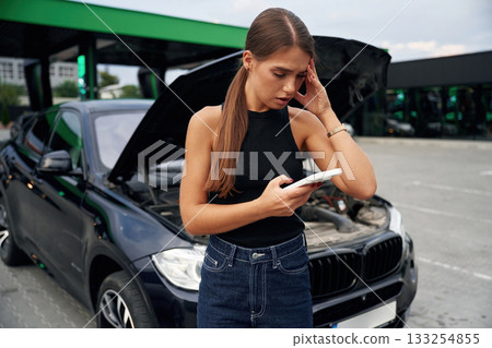 Woman's car is broken, accident, standing outdoors 133254855