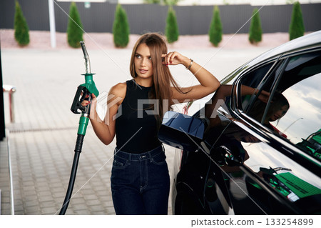 Standing and posing. A young woman at a gas station with her car Standing and posing. A young woman at a gas station with her car 133254899