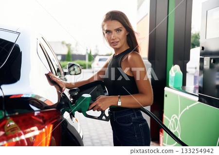 A young woman at a gas station with her car 133254942