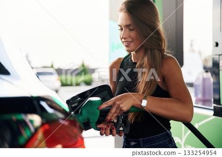 Process of refilling. A young woman at a gas station with her car 133254954
