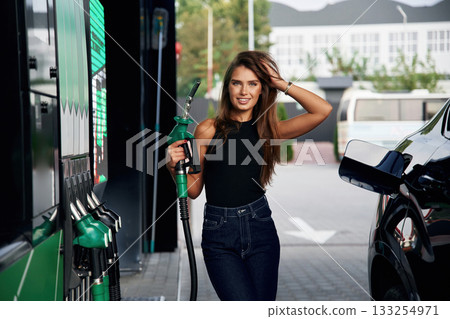 Fuel for the automobile. A young woman at a gas station with her car Fuel for the automobile. A young woman at a gas station with her car 133254971