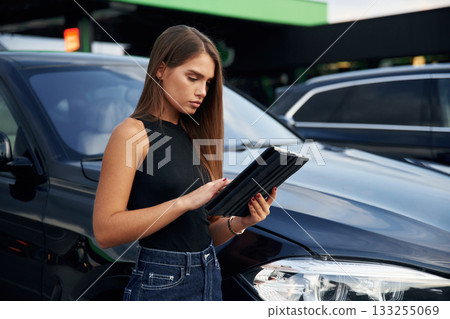 Digital tablet in hands. Woman is near her car outdoors 133255069