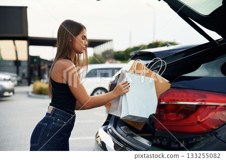 Trunk is opened. Woman is near her car outdoors 133255082