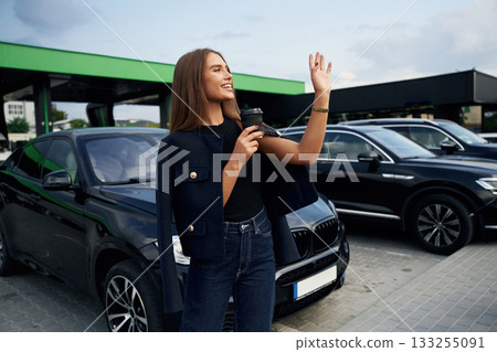 Hello gesture. A young woman at a gas station with her car Hello gesture. A young woman at a gas station with her car 133255091