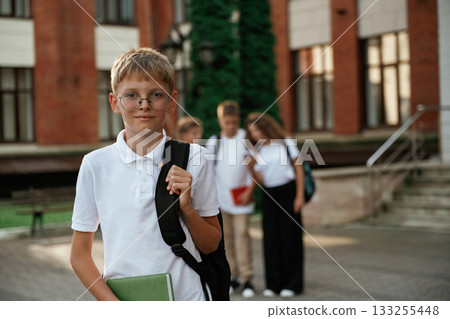 Standing and posing. Kids are near the school together, pupils 133255448