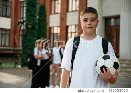 Boy is with soccer ball. Kids are near the school together, pupils Boy is with soccer ball. Kids are near the school together, pupils 133255453