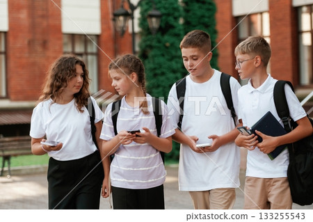 Smartphones in hands. Kids are near the school together, pupils 133255543