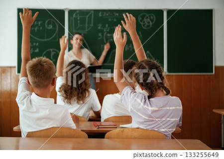 With hands up. Pupils, kids in the classroom together With hands up. Pupils, kids in the classroom together 133255649