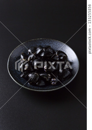 Large Yamato Shijimi clams on a plate against a black background 133255856