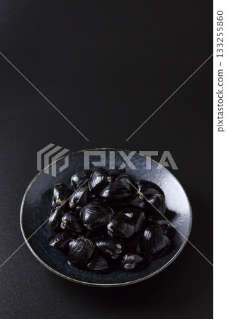 Large Yamato Shijimi clams on a plate against a black background 133255860