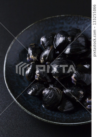 Large Yamato Shijimi clams on a plate against a black background Large Yamato Shijimi clams on a plate against a black background 133255866