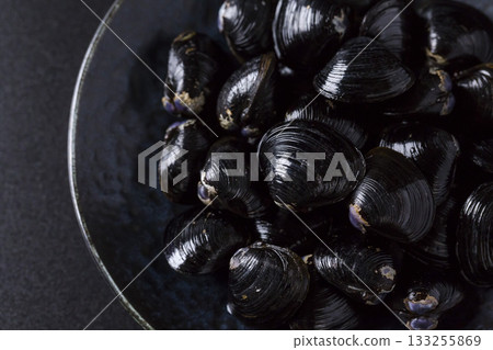 Large Yamato Shijimi clams on a plate against a black background 133255869