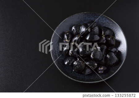 Large Yamato Shijimi clams on a plate against a black background Large Yamato Shijimi clams on a plate against a black background 133255872