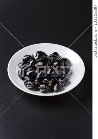Large Yamato Shijimi clams on a plate against a black background 133255897