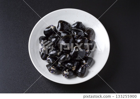 Large Yamato Shijimi clams on a plate against a black background Large Yamato Shijimi clams on a plate against a black background 133255900
