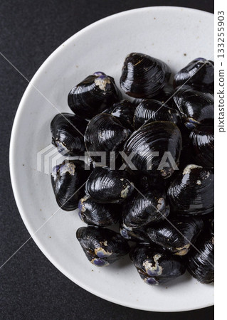 Large Yamato Shijimi clams on a plate against a black background Large Yamato Shijimi clams on a plate against a black background 133255903