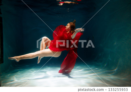 white synchronized swimmer practicing underwater in red dress white synchronized swimmer practicing underwater in red dress 133255933