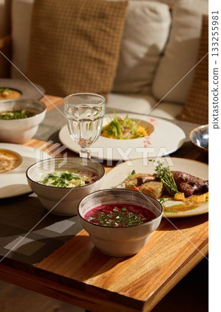 A Variety of Delicious Dishes Served on a Beautiful Wooden Table with a Cozy Ambiance 133255981