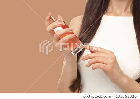 Woman with long hair holds a perfume bottle in an elegant setting 133256326