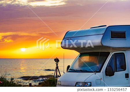 Camper and camera on tripod on beach at sunrise Camper and camera on tripod on beach at sunrise 133256457