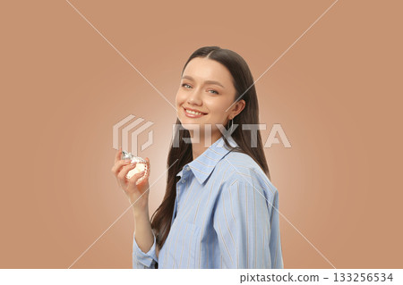 Woman happily poses with a perfume bottle in hand 133256534