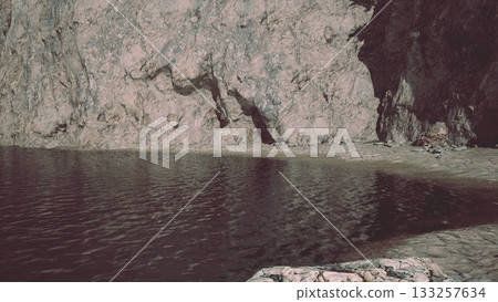 Gentle waves lap against a sandy shore, while impressive cliffs rise majestically in the background. This peaceful scene captures the beauty of nature at a secluded spot during the day. Gentle waves lap against a sandy shore, while impressive cliffs rise majestically in the background. This peaceful scene captures the beauty of nature at a secluded spot during the day. 133257634
