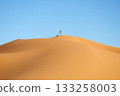 A desert landscape with a blue sky and footprints in the sand 133258003