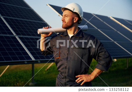 Taking a break, standing. Man is working with solar panels outdoors at daytime Taking a break, standing. Man is working with solar panels outdoors at daytime 133258112