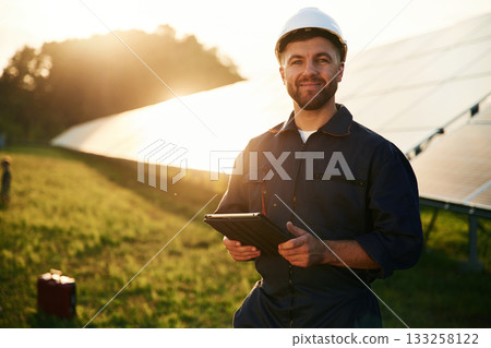 Reflection of the sunlight behind. Man is working with solar panels outdoors at daytime 133258122
