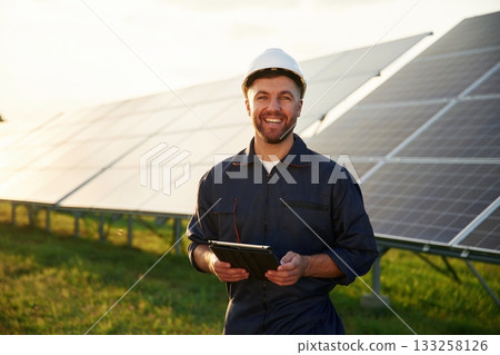 Digital tablet in hands. Man is working with solar panels outdoors at daytime 133258126