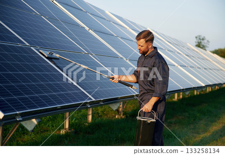 Man is working with solar panels outdoors at daytime Man is working with solar panels outdoors at daytime 133258134
