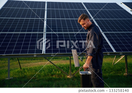 Side view, cleaning service. Man is working with solar panels outdoors at daytime 133258140