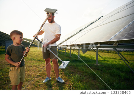 Time to clean the surface. Father with his little son are together near the solar panels 133258465