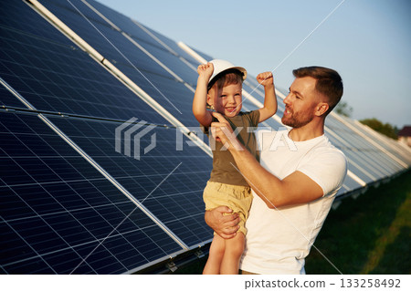 White hard hat. Father with his little son are together near the solar panels White hard hat. Father with his little son are together near the solar panels 133258492