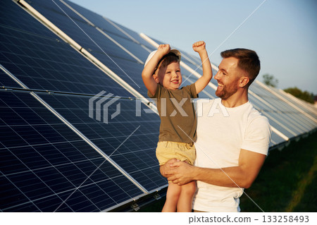 White hard hat. Father with his little son are together near the solar panels White hard hat. Father with his little son are together near the solar panels 133258493