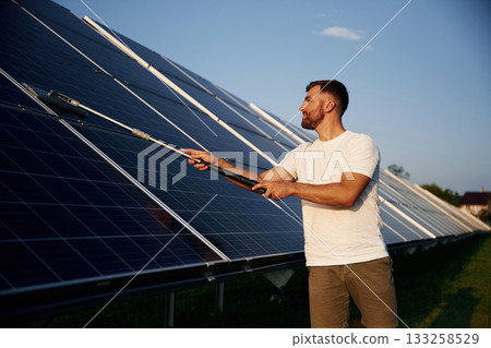 Professional cleaning. Man is working with solar panels outdoors at daytime 133258529