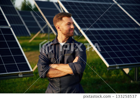Portrait, standing with arms crossed. Man is working with solar panels outdoors at daytime 133258537