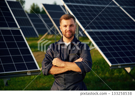 Portrait, standing with arms crossed. Man is working with solar panels outdoors at daytime 133258538