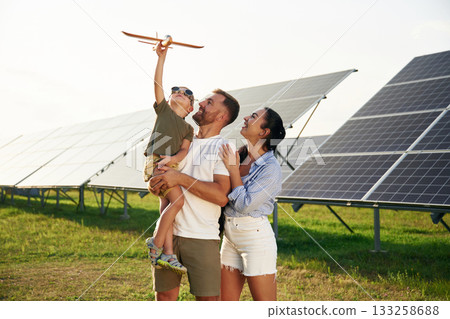 Family is together. Father, mother and little son are outdoors near solar panels Family is together. Father, mother and little son are outdoors near solar panels 133258688