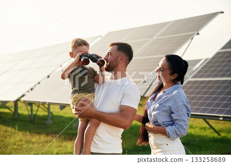 Family is together. Father, mother and little son are outdoors near solar panels Family is together. Father, mother and little son are outdoors near solar panels 133258689