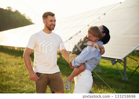 Embracing each other. Father, mother and little son are outdoors near solar panels 133258696