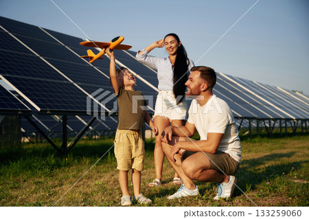 Imagination conception, with toy plane. Father, mother and little son are outdoors near solar panels 133259060
