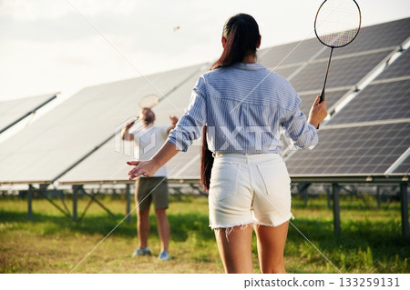 Playing badminton. Couple are having fun near the solar panels outdoors 133259131