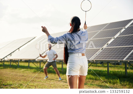 Playing badminton. Couple are having fun near the solar panels outdoors 133259132