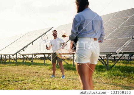 Playing badminton. Couple are having fun near the solar panels outdoors 133259133